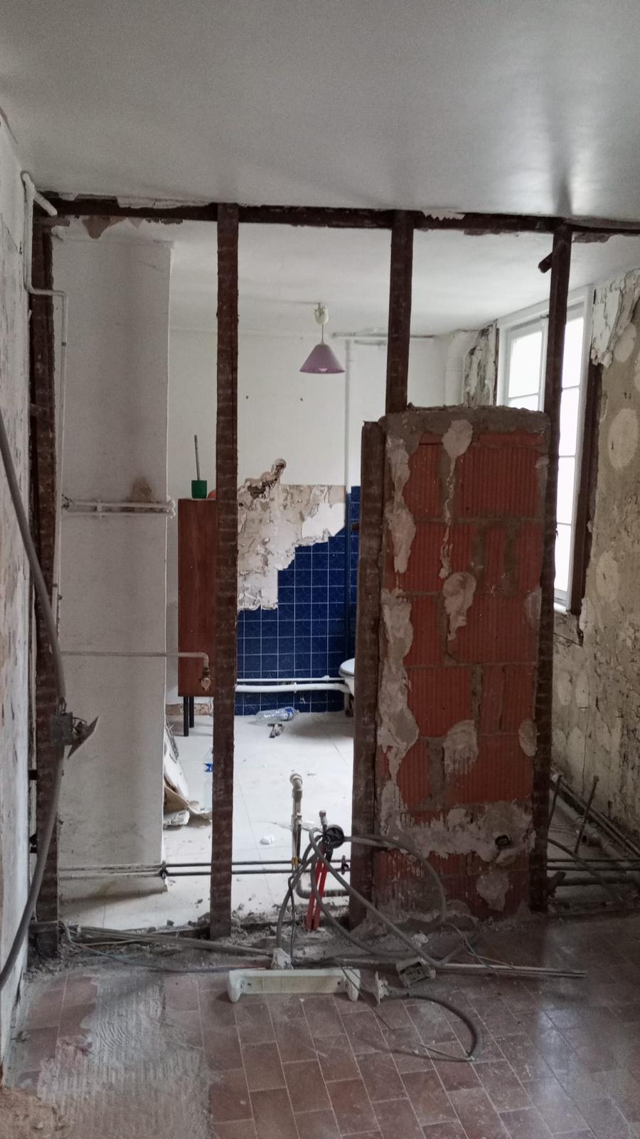 Salle de bain après démolition avec carrelage bleu encore visible