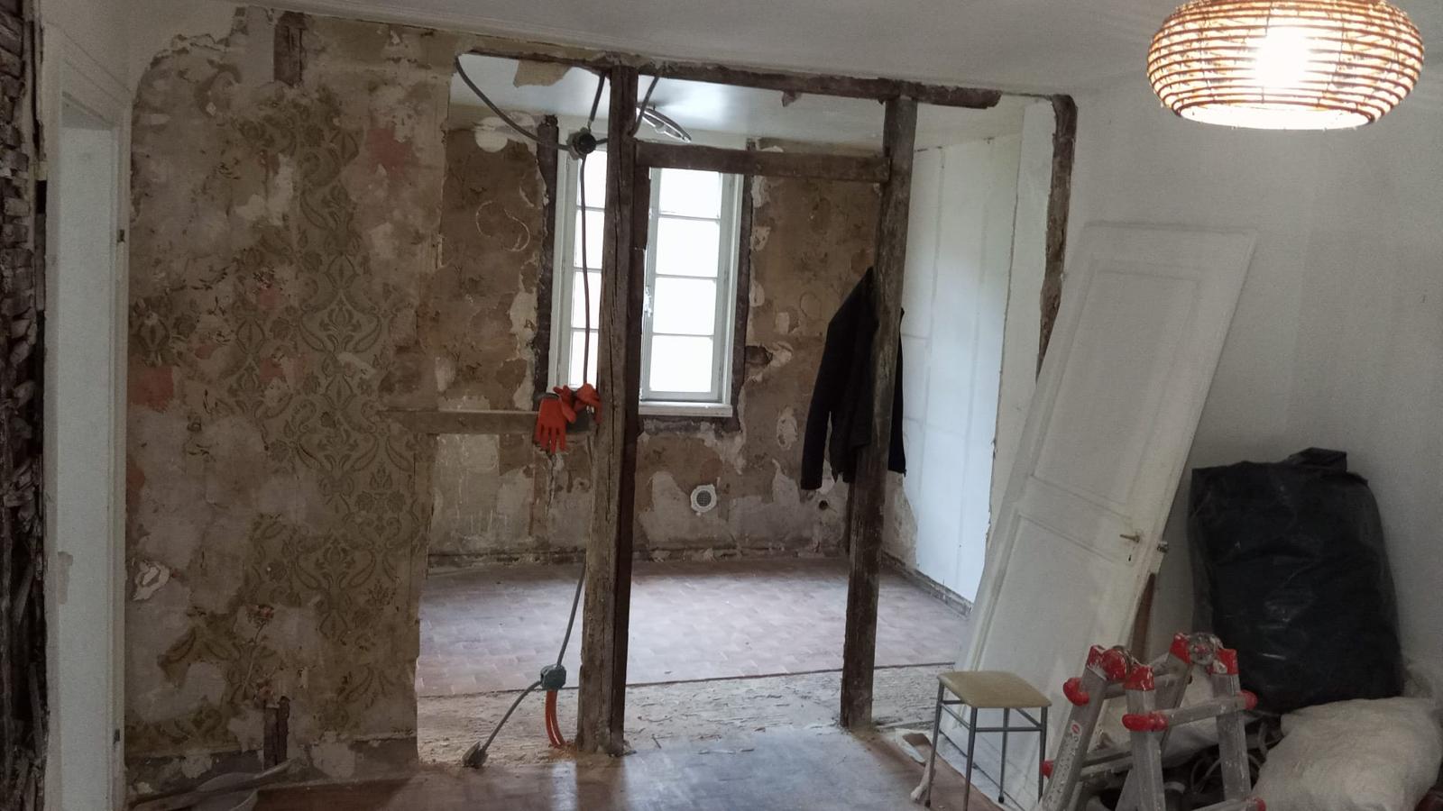 Salon avec structure en bois apparente et murs décapés après démolition